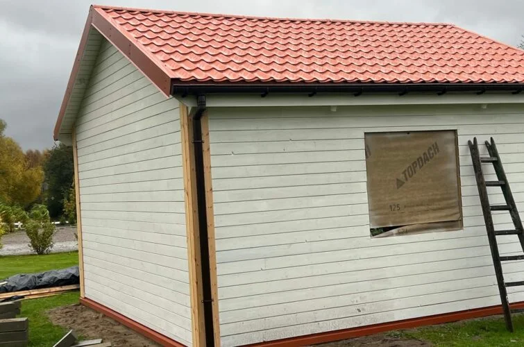 Domek letniskowy NekoDom z jasną elewacją drewnianą i czerwonym dachem